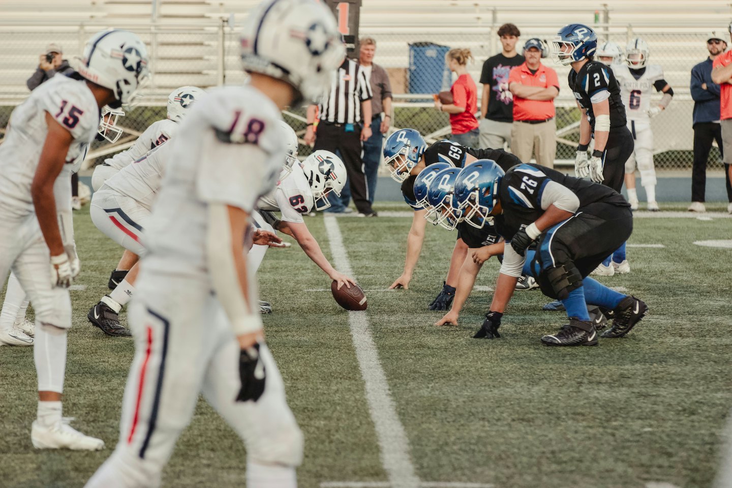 Football players line up on a turf field for a play.