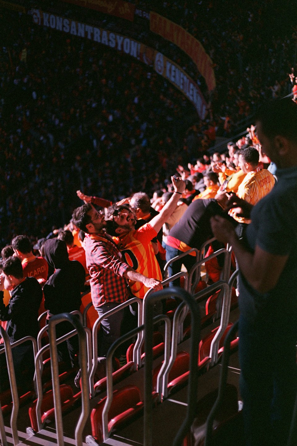 Sports fans cheer during a match in a crowded stadium.